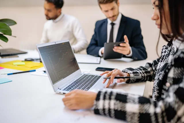 Professional team working on stock market analysis with laptops and tablets in modern office setting. Financiering van groei: van banklening tot investeerder