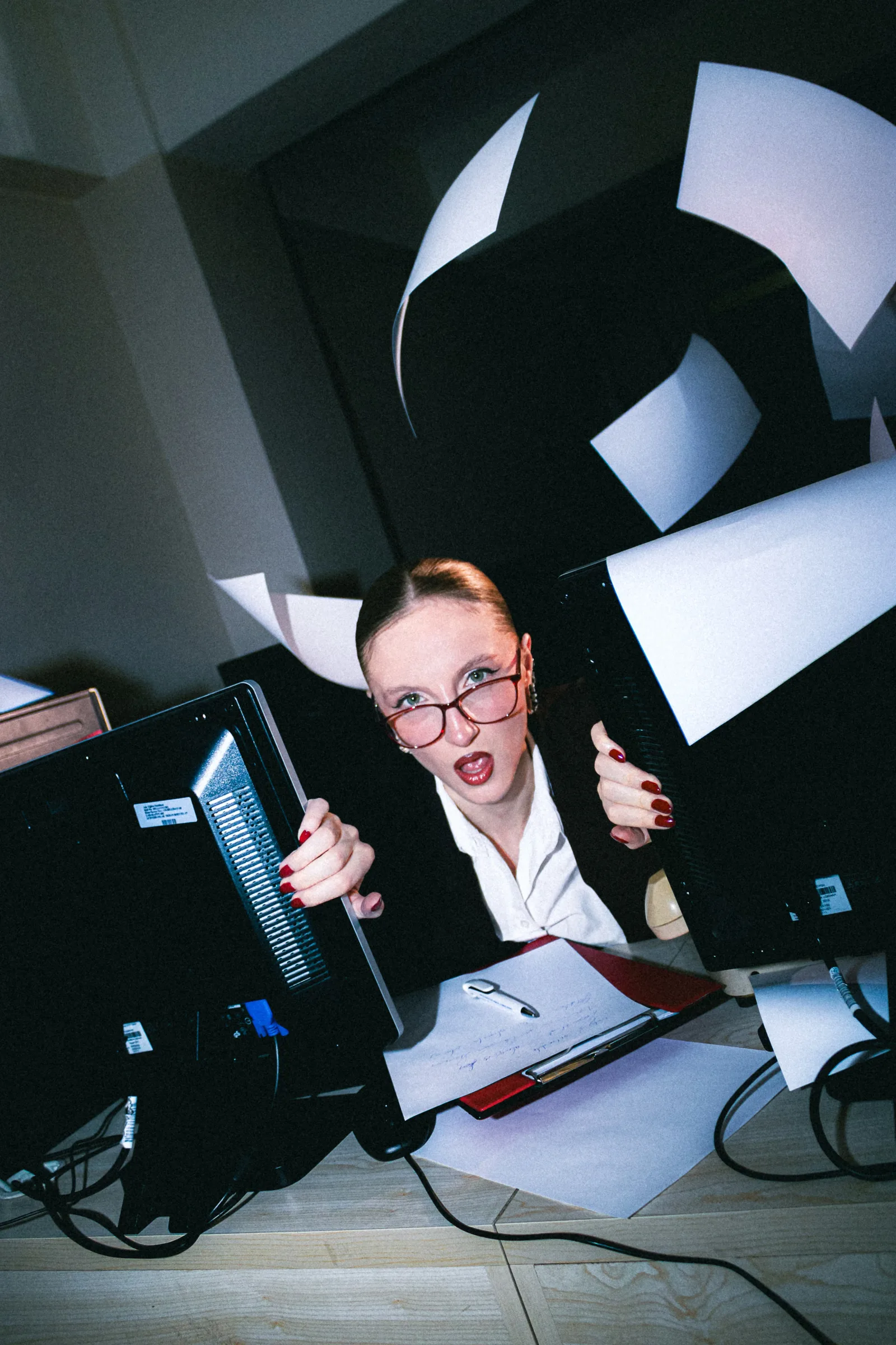 Office worker overwhelmed by papers in chaotic work environment.